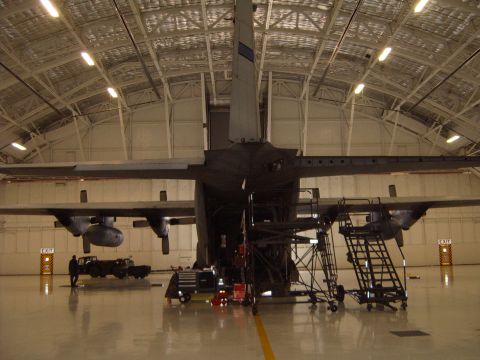 1988 Ford Bronco - A large military cargo plane is parked inside a hangar, surrounded by maintenance equipment and scaffolding.