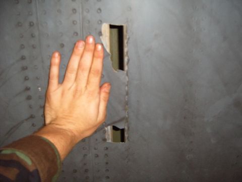 1988 Ford Bronco - A hand is placed on a gray metal panel that has two rectangular holes cut into it.