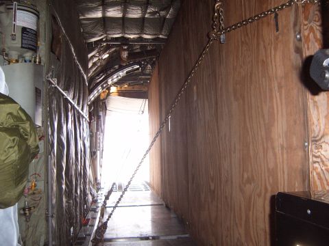 1988 Ford Bronco - View inside the cargo area of an aircraft, showing tie-down chains and wooden walls.