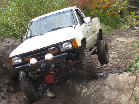 1990 Ford Bronco - This Toyota pickup truck appears to be from the mid-1980s, not a 1990 Ford Bronco, as it navigates a challenging off-road course.