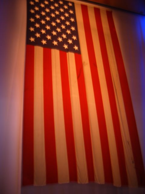 1988 Ford Bronco - An American flag is displayed indoors, illuminated by colored lights, with a website logo in the corner.