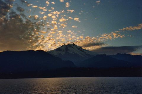 2001 Ford Taurus - A mountain looms over a calm lake under a dramatic sky filled with clouds at sunset.