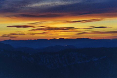 2001 Ford Taurus - A vibrant sunset paints the sky with orange and yellow hues over silhouetted mountain ranges, with "SUPERMOTORS" visible at the bottom.