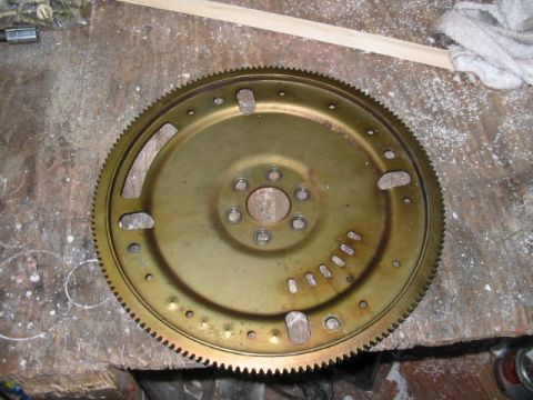 1997 Ford Crown Victoria - A close-up view of a flywheel, a crucial component in a vehicle's powertrain, resting on a wooden surface.