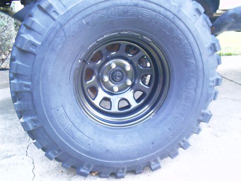 1983 Chevrolet Silverado 1500 - Off-road tire mounted on a black steel wheel, with visible text on the tire sidewall.