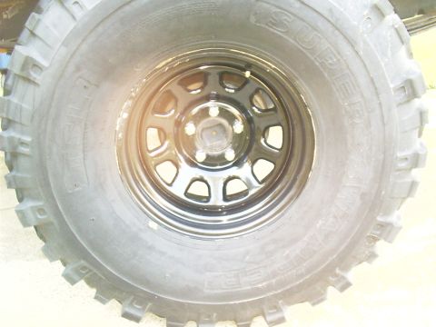 1983 Chevrolet Silverado 1500 - A close-up view shows the aggressive tread pattern of a large off-road tire mounted on a black steel wheel.