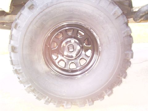 1983 Chevrolet Silverado 1500 - Close-up of a vehicle's tire and black steel wheel, with part of the frame visible.