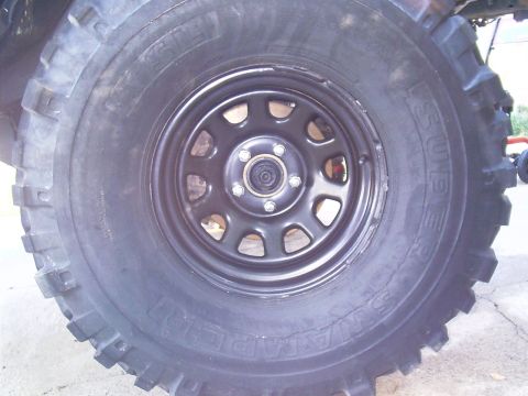 1983 Chevrolet Silverado 1500 - This image shows a close-up view of a tire mounted on a black steel wheel, with visible text on the tire sidewall.