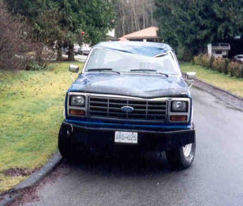 1989 Ford Bronco - This blue Ford Bronco shows significant damage to its roof and hood, suggesting a rough history.