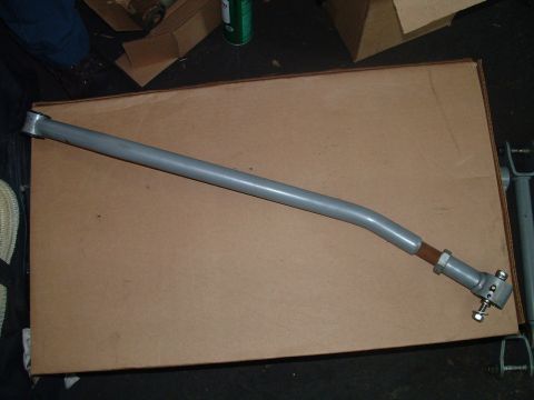 1994 Ford Bronco - A gray metal automotive part, possibly a suspension or steering component, is shown against a cardboard background.