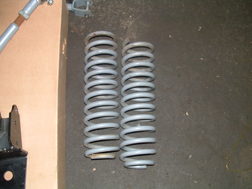 Two gray coil springs on a dark floor next to a cardboard box
