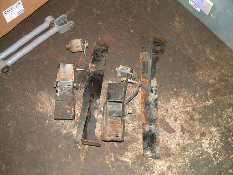 1994 Ford Bronco - Collection of vehicle suspension parts, including control arms, laid out on a workshop floor.