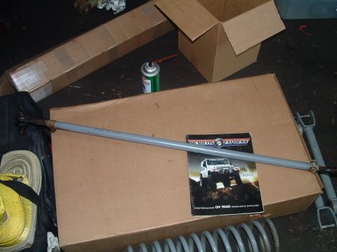 1994 Ford Bronco - A tie rod assembly and a 2004 Rubicon Express catalog are laid out on cardboard boxes.