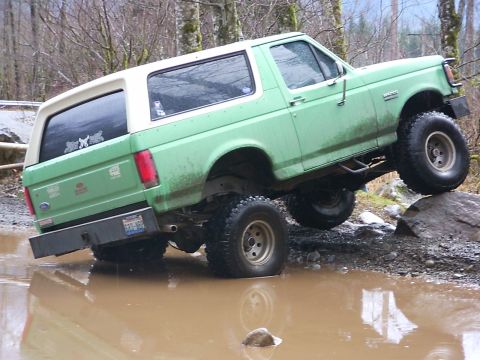 1990 Ford Bronco - This 1990 Ford Bronco is navigating a challenging off-road course with one wheel up on a rock.
