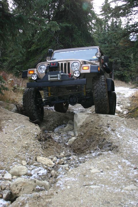 2003 Jeep TJ - 2003 Jeep TJ tackles a challenging off-road obstacle on a wooded trail.
