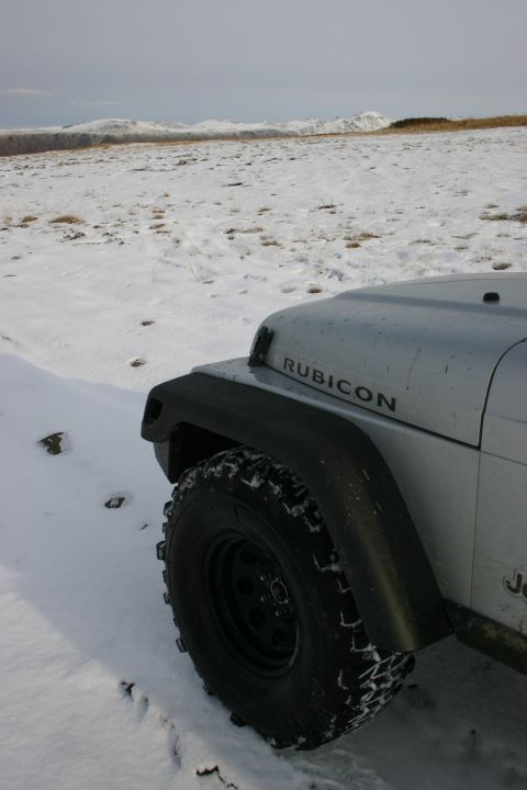2003 Jeep TJ - Silver Jeep Wrangler Rubicon parked in a snowy field with mountains in the background.
