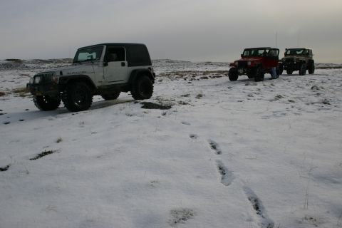 2003 Jeep TJ - Three Jeep Wranglers drive through a snowy, barren landscape under an overcast sky.