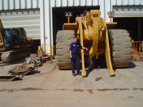 1966 International School Bus - Man poses with a huge wheel loader; an excavator is visible to the left.