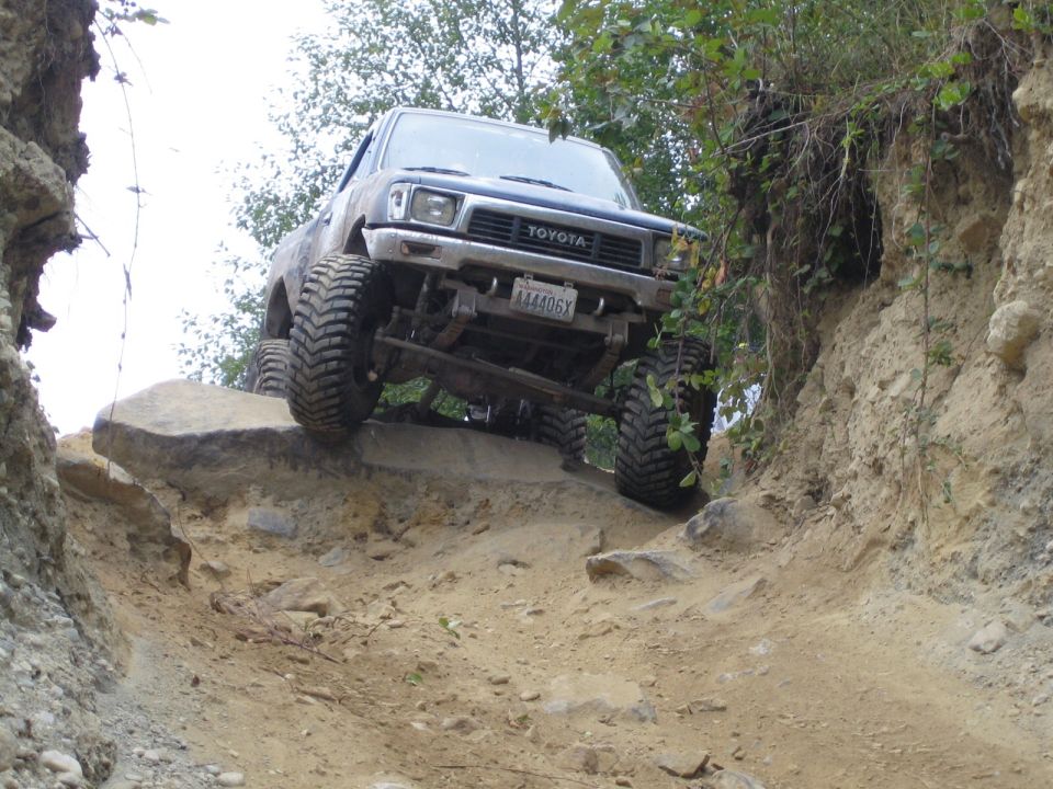 Toyota pickup truck with large tires climbing over rocks on a dirt trail