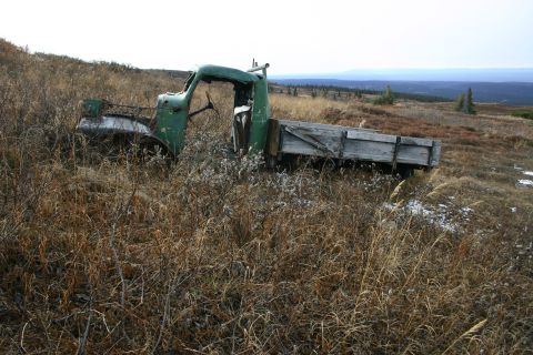 2003 Jeep TJ - An abandoned vintage truck rests in a grassy field, its wooden bed weathered by time.