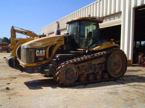 1966 International School Bus - Caterpillar Challenger tractor and excavator parked outdoors near a large building.