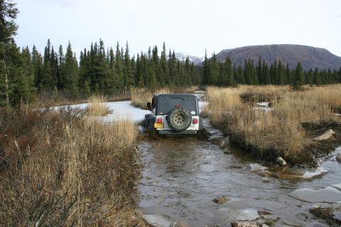 2003 Jeep TJ - Jeep TJ navigates a challenging off-road path with mud and ice.