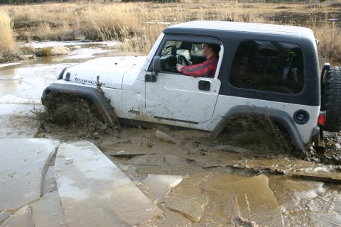 2003 Jeep TJ - A white Jeep Wrangler TJ is stuck in a muddy, icy terrain with its tires submerged.