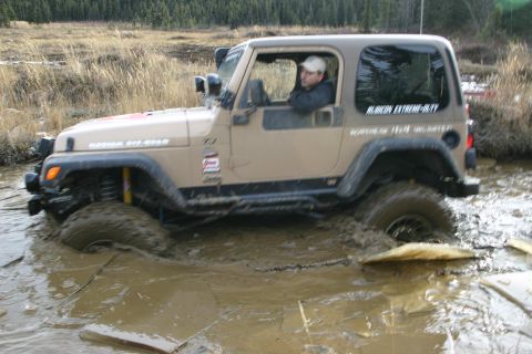 2003 Jeep TJ - A tan Jeep Wrangler TJ navigates a muddy off-road trail.