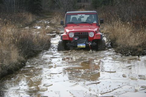2003 Jeep TJ - Red 2003 Jeep TJ navigates an icy water obstacle on an off-road trail.