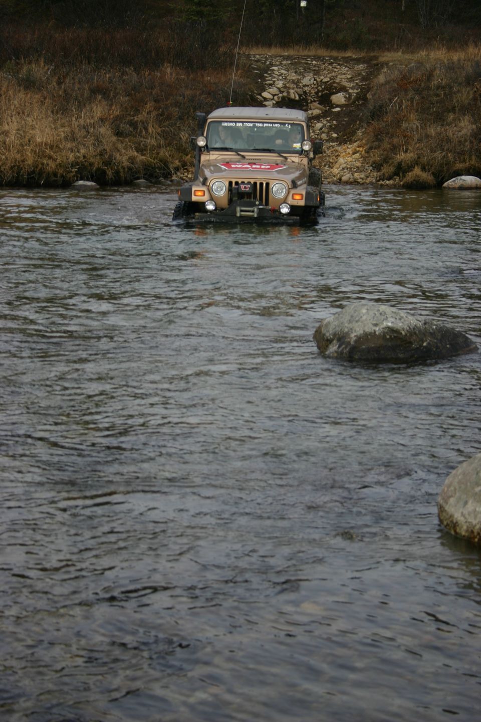 2003 Jeep TJ driving through a river with a WARN winch on the front