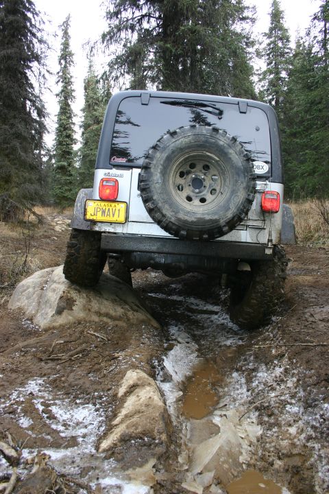 2003 Jeep TJ - A Jeep TJ navigates a challenging off-road course with muddy terrain and icy patches.