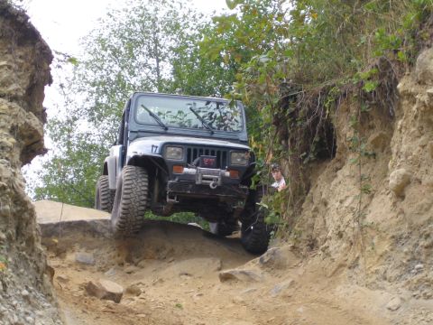 1990 Ford Bronco - A Jeep Wrangler navigates a challenging off-road path with steep, eroded sides.