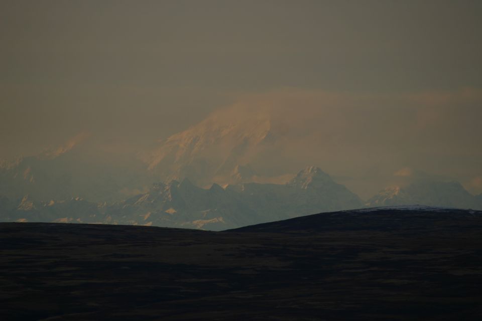 mountain range under hazy sky, dark foreground hills