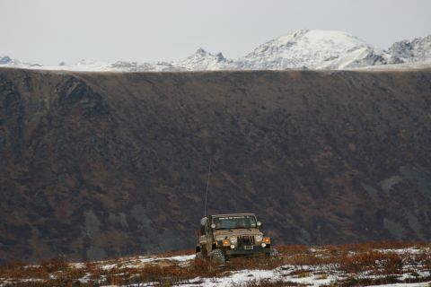 2003 Jeep TJ - A Jeep TJ is parked on a barren, snow-dusted hillside with a dark, textured mountain range behind it.