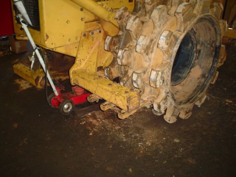 1966 International School Bus - A yellow compactor roller is supported by a red hydraulic jack.