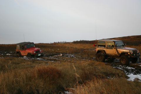 2003 Jeep TJ - A silver Jeep pulls a red Jeep out of the mud during an off-road excursion.