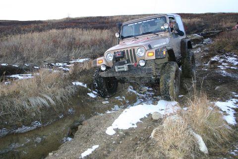 2003 Jeep TJ - Jeep TJ tackling an off-road trail with snow and mud.