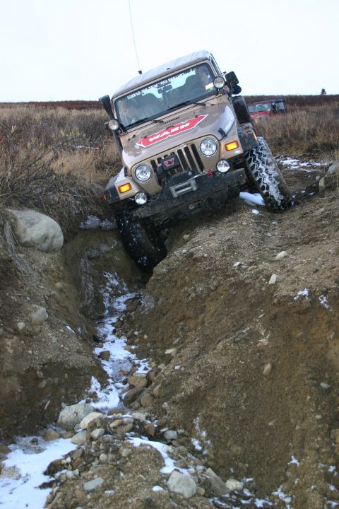 2003 Jeep TJ - A 2003 Jeep TJ navigates a challenging off-road terrain with a second vehicle visible in the background.