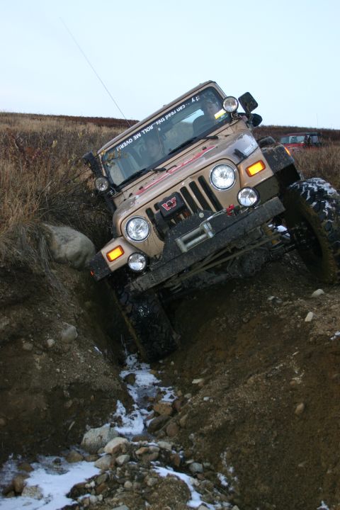 2003 Jeep TJ - 2003 Jeep TJ tackling an off-road obstacle with snow and ice on the trail.