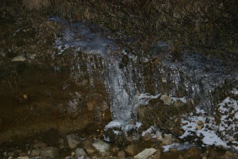 2003 Jeep TJ - A frozen stream flows over rocks and dry grass, with icicles hanging from the bank.
