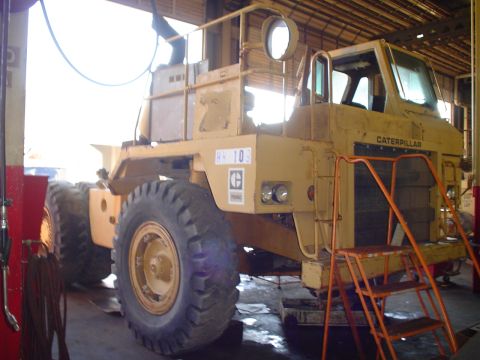1966 International School Bus - Yellow Caterpillar wheel loader undergoing maintenance in a workshop environment.