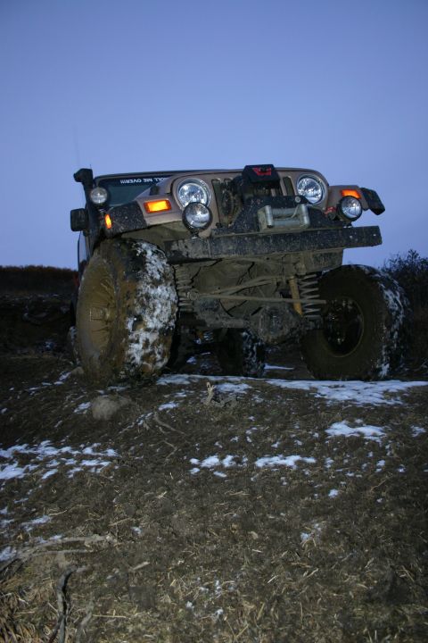 2003 Jeep TJ - A 2003 Jeep TJ navigates a muddy and snowy trail during twilight.