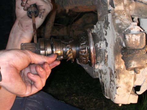 1989 Ford Bronco - Mechanic works on a vehicle's axle and hub assembly, showing a close-up of the splined shaft.
