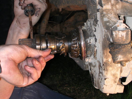 Close-up of a greasy vehicle axle splined shaft being removed from a hub assembly
