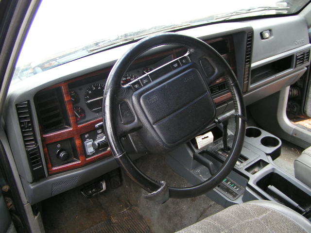 Jeep Cherokee interior: steering wheel with Jeep airbag, woodgrain dash trim, gauges, and automatic shifter