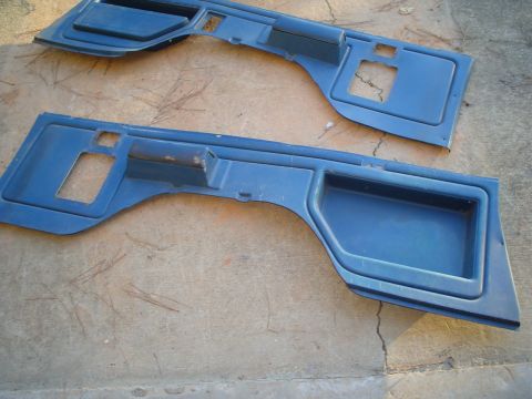 1984 Ford Bronco - Two blue plastic interior door panels are laid out on a concrete surface.