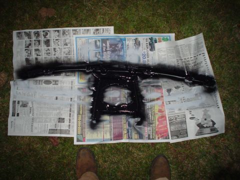 1984 Ford Bronco - Car part being spray painted black, resting on old newspapers.