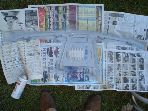 1984 Ford Bronco - A car part is being painted, laid out on newspapers with a spray can nearby.