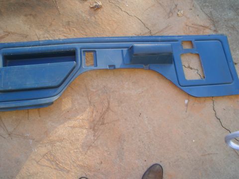 1984 Ford Bronco - A blue plastic door panel, likely from an older vehicle, is shown laid out on a concrete surface.