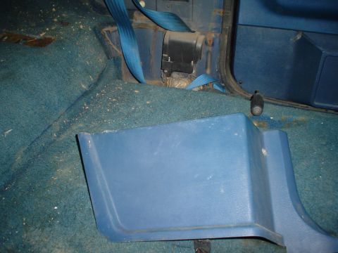 1984 Ford Bronco - Close-up view of the interior floor and seatbelt anchor point of a vehicle.